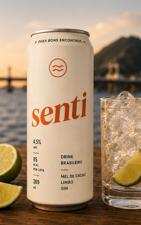 Lata de Senti sobre uma mesa de madeira, com copo de gin gelado, limão e a Terceira Ponte de Vitória ao fundo no pôr do sol